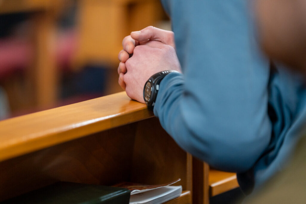 Biddende handen in kerkbank